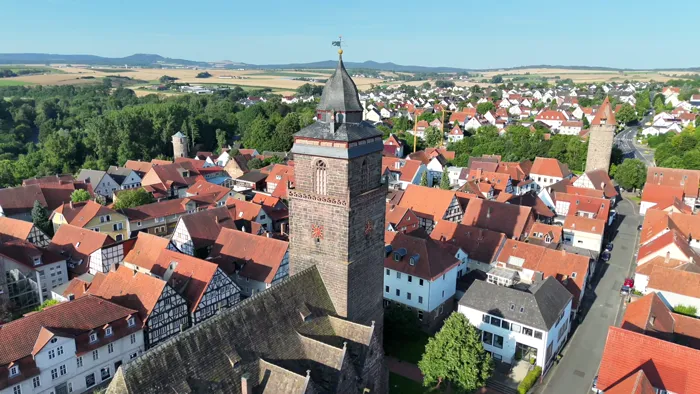 Gotische Stadtkirche mit hohem Westturm zwischen Fachwerkhäusern aus der Luft