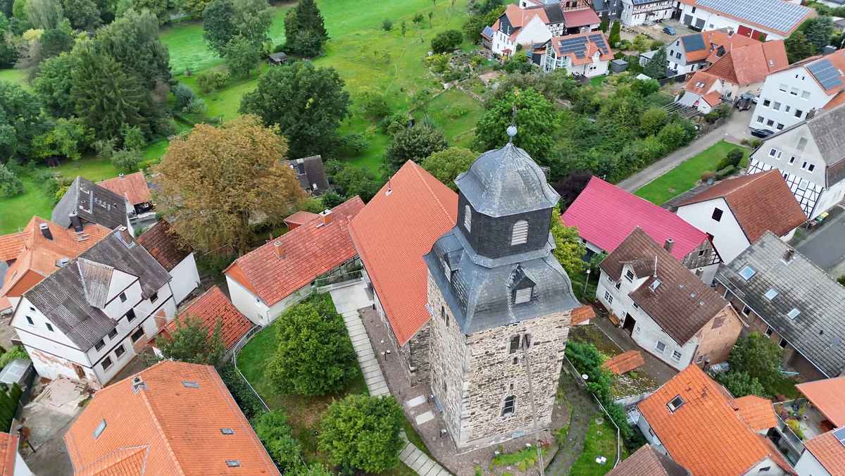 Kirchturm mit Haube von oben, rundherum Wohnhäuser, Gärten und Bäume auf dem Kirchberg