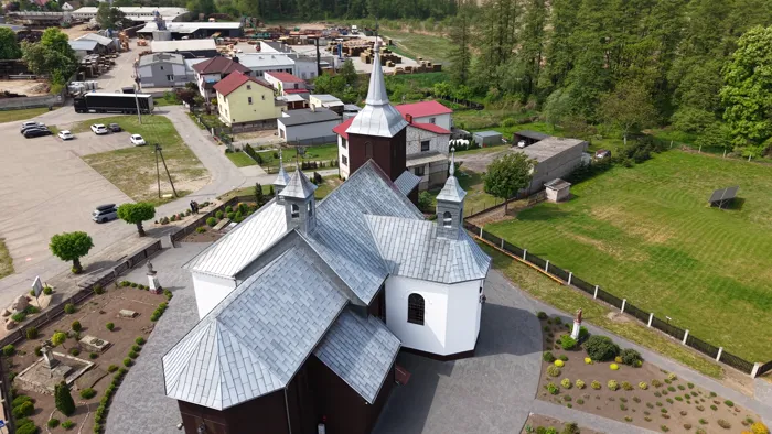 Holzkirche mit Turm und weißer Kapelle aus der Luft